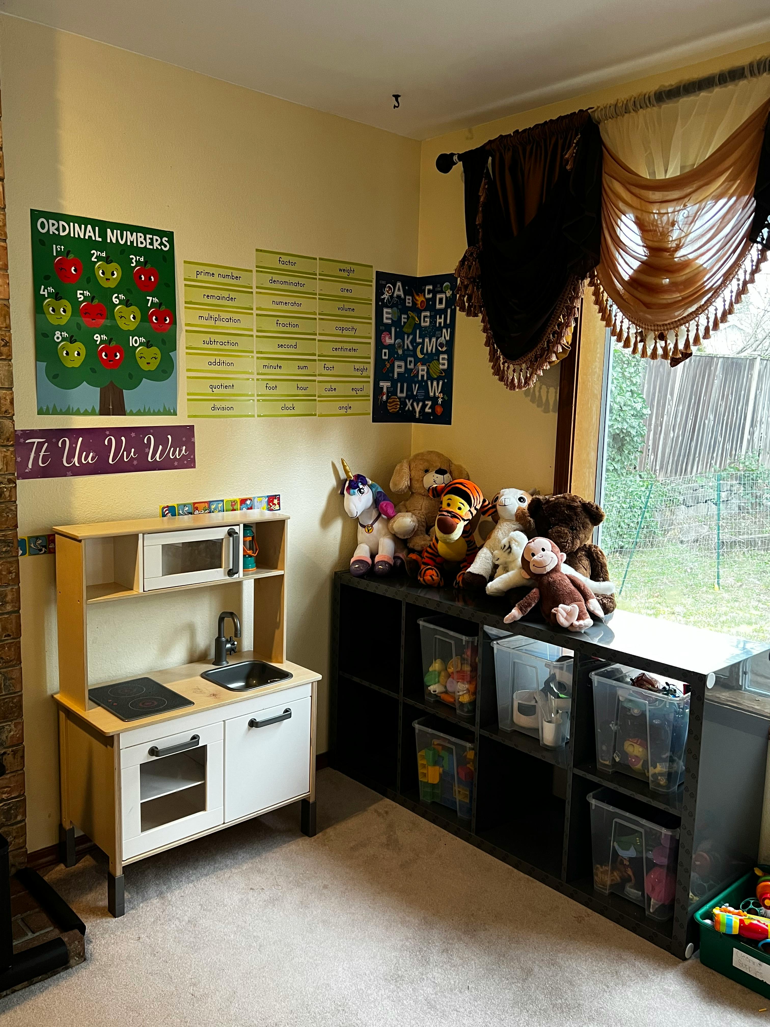 Child's play kitchen and toy storage shelves with stuffed animals