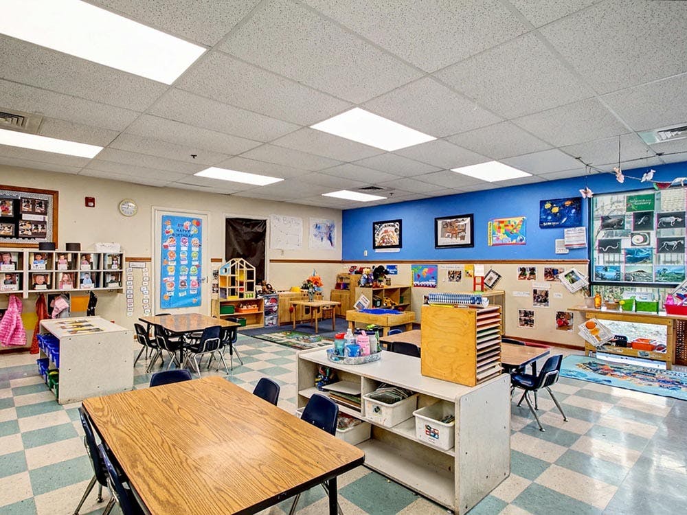 Empty classroom with tables, chairs, and shelves