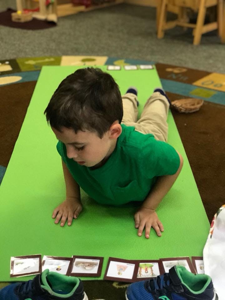 Child lying on stomach on a green mat looking at cards