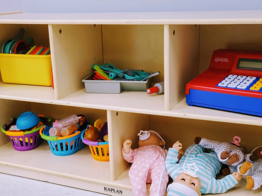 Shelves with toys including a toy cash register, baskets, and dolls