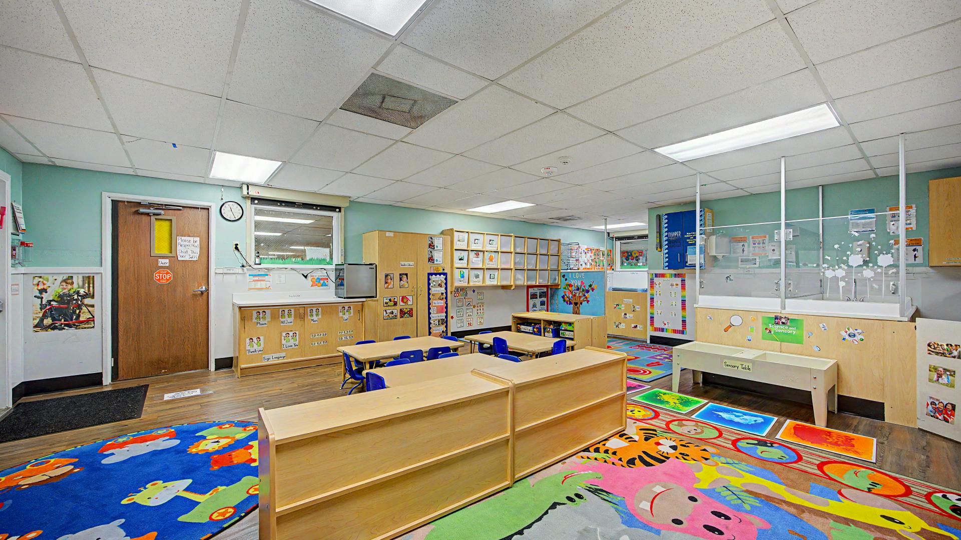 Classroom with tables, chairs, storage, and colorful rugs