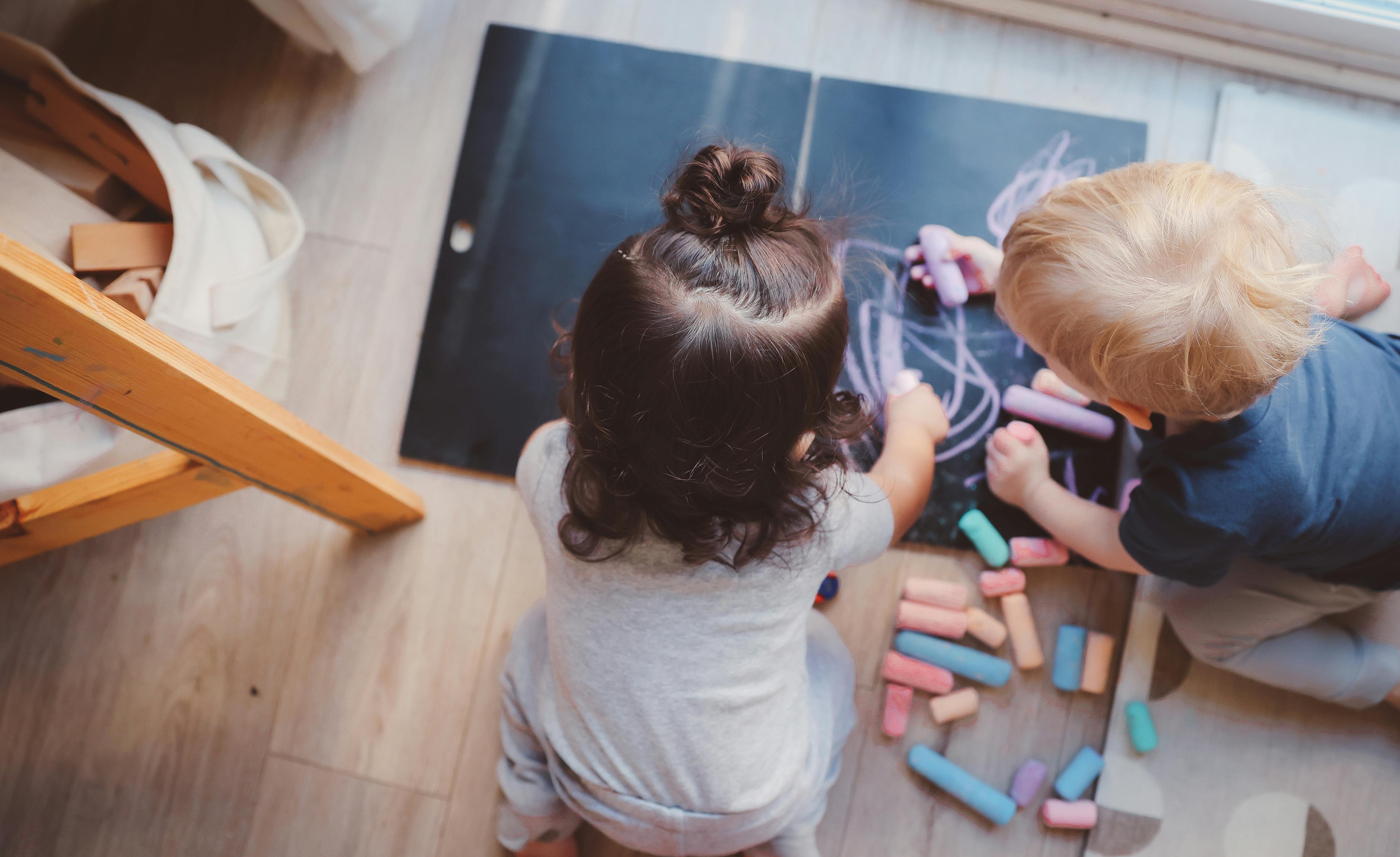 Two children drawing with chalk on a chalkboard