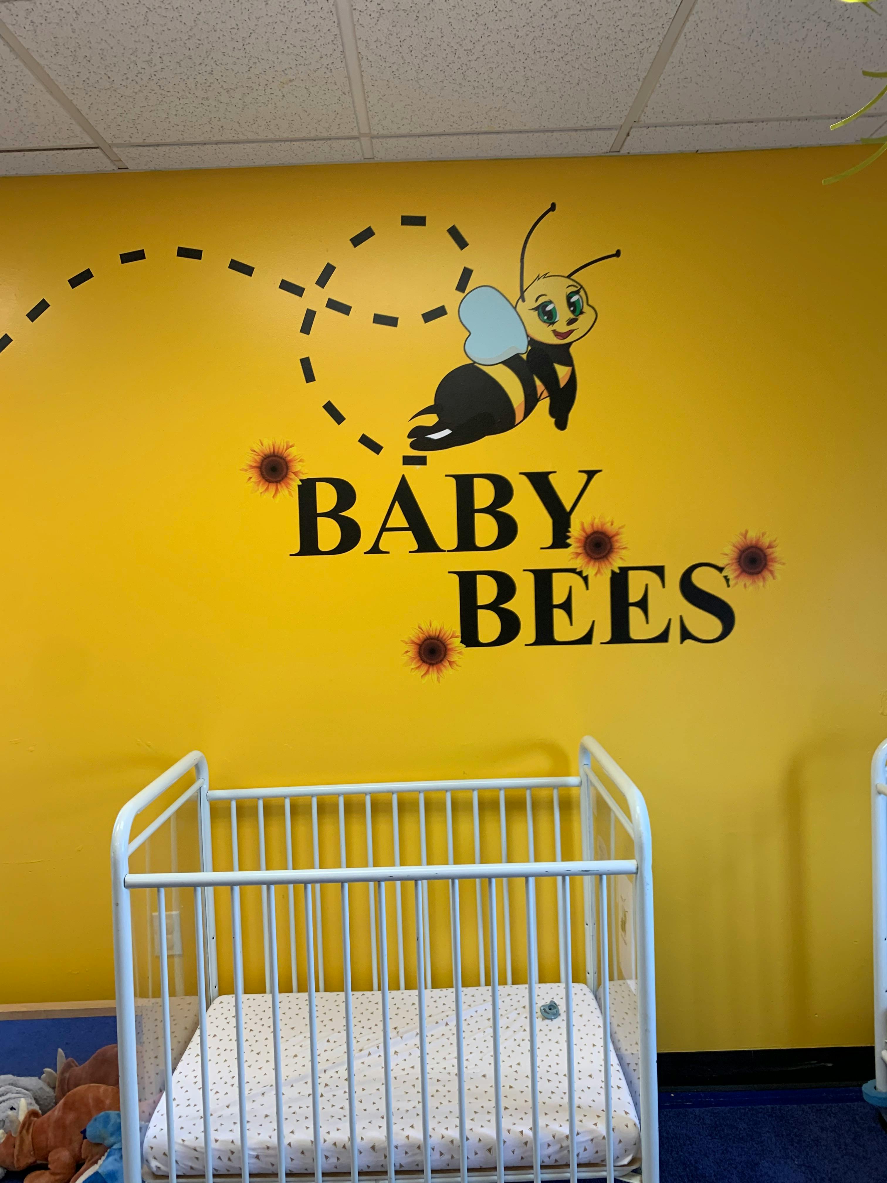 Yellow wall with a bee graphic and the words "BABY BEES" above a white crib