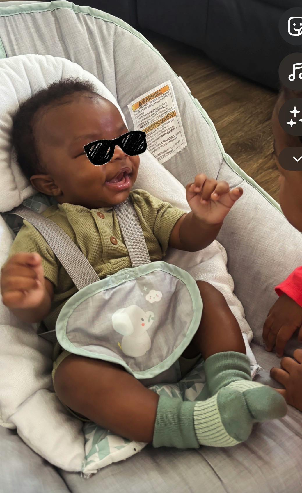 Baby in a bouncer wearing sunglasses and socks