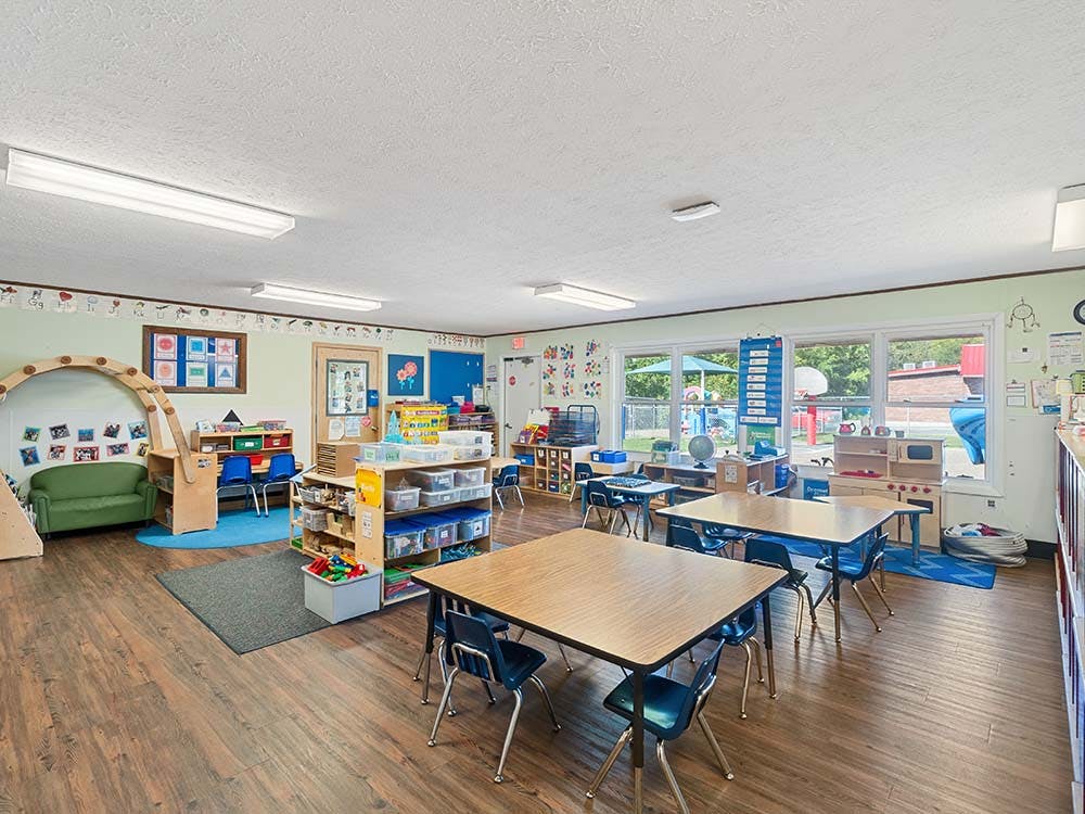 An empty preschool classroom with small tables and chairs