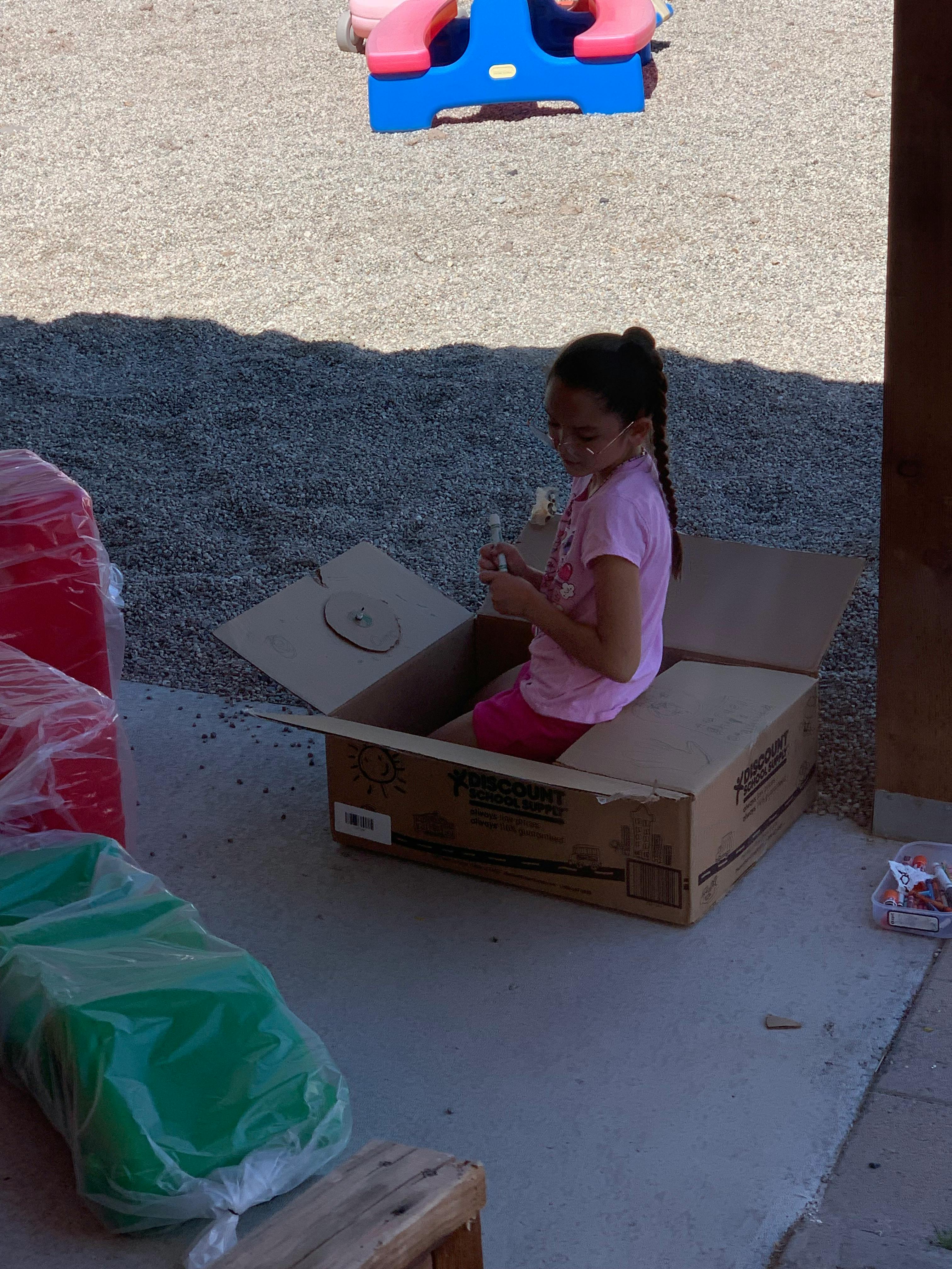 Child sitting inside a large cardboard box