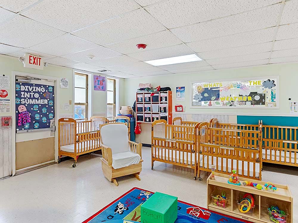 Baby room with multiple cribs, a rocking chair, and child-friendly decorations
