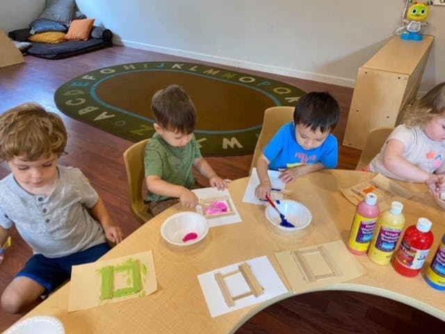 Children painting at a table in a classroom