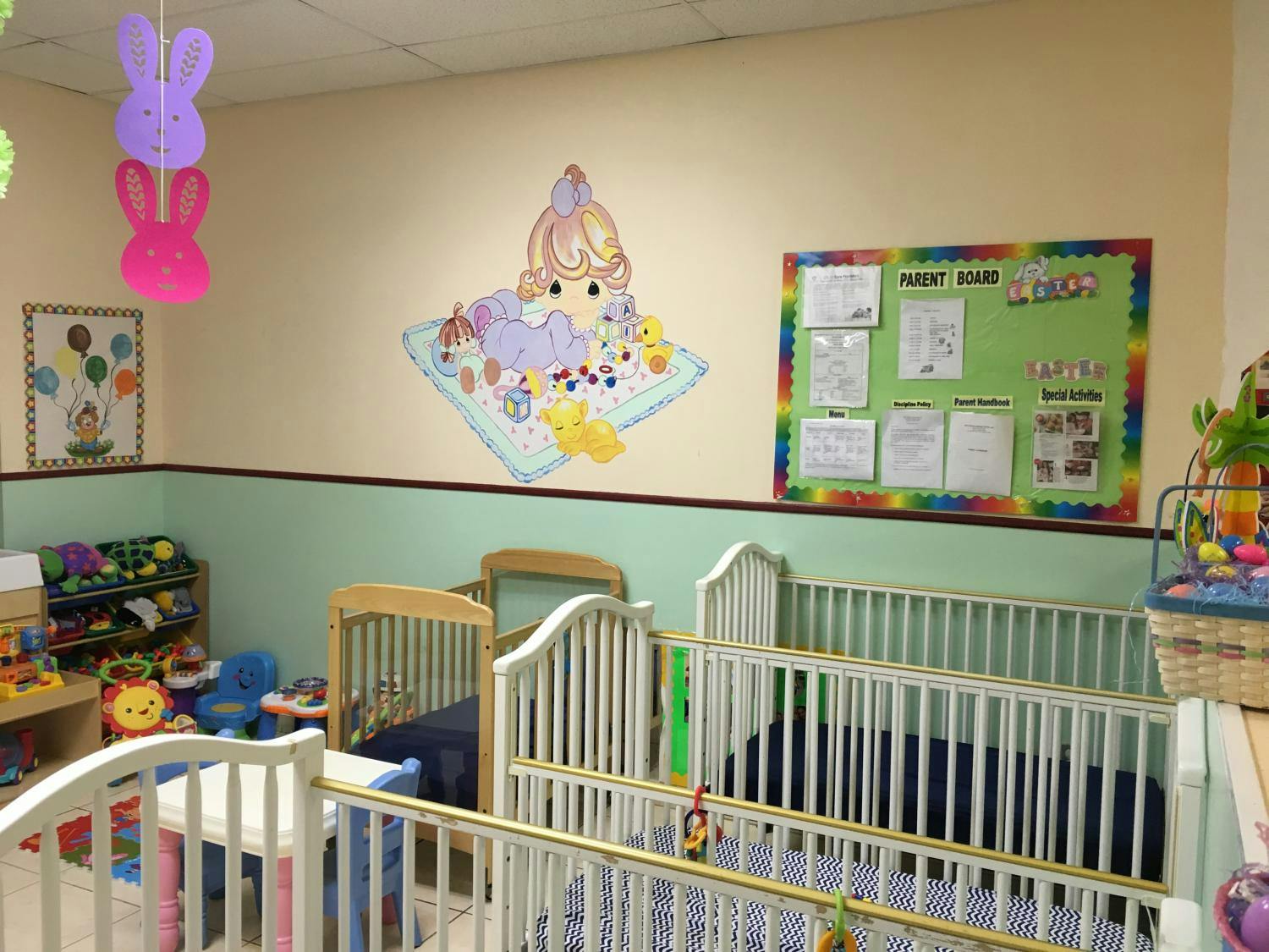 Cribs in a nursery room with wall decorations