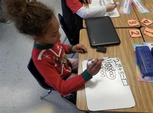 Child writing on a whiteboard at a desk