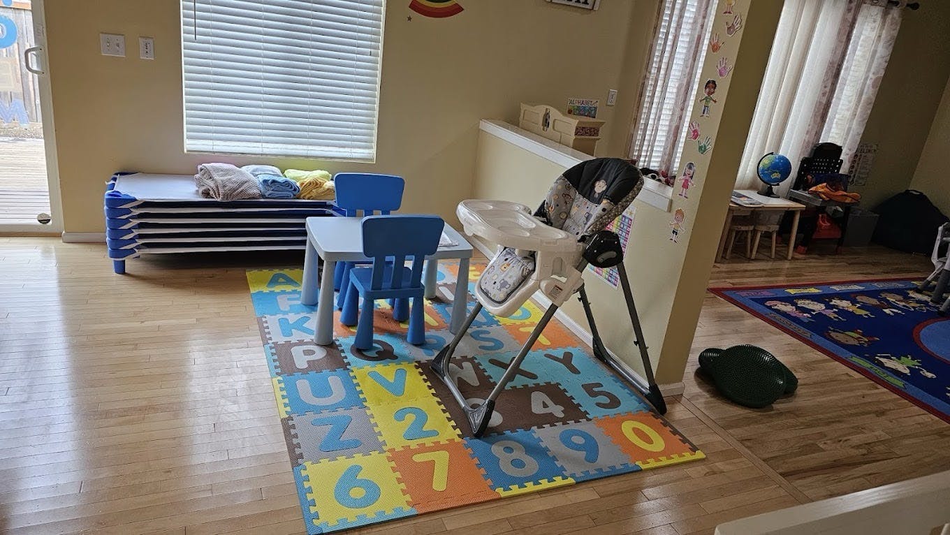 Children's classroom area with cots, small tables and chairs, and a high chair