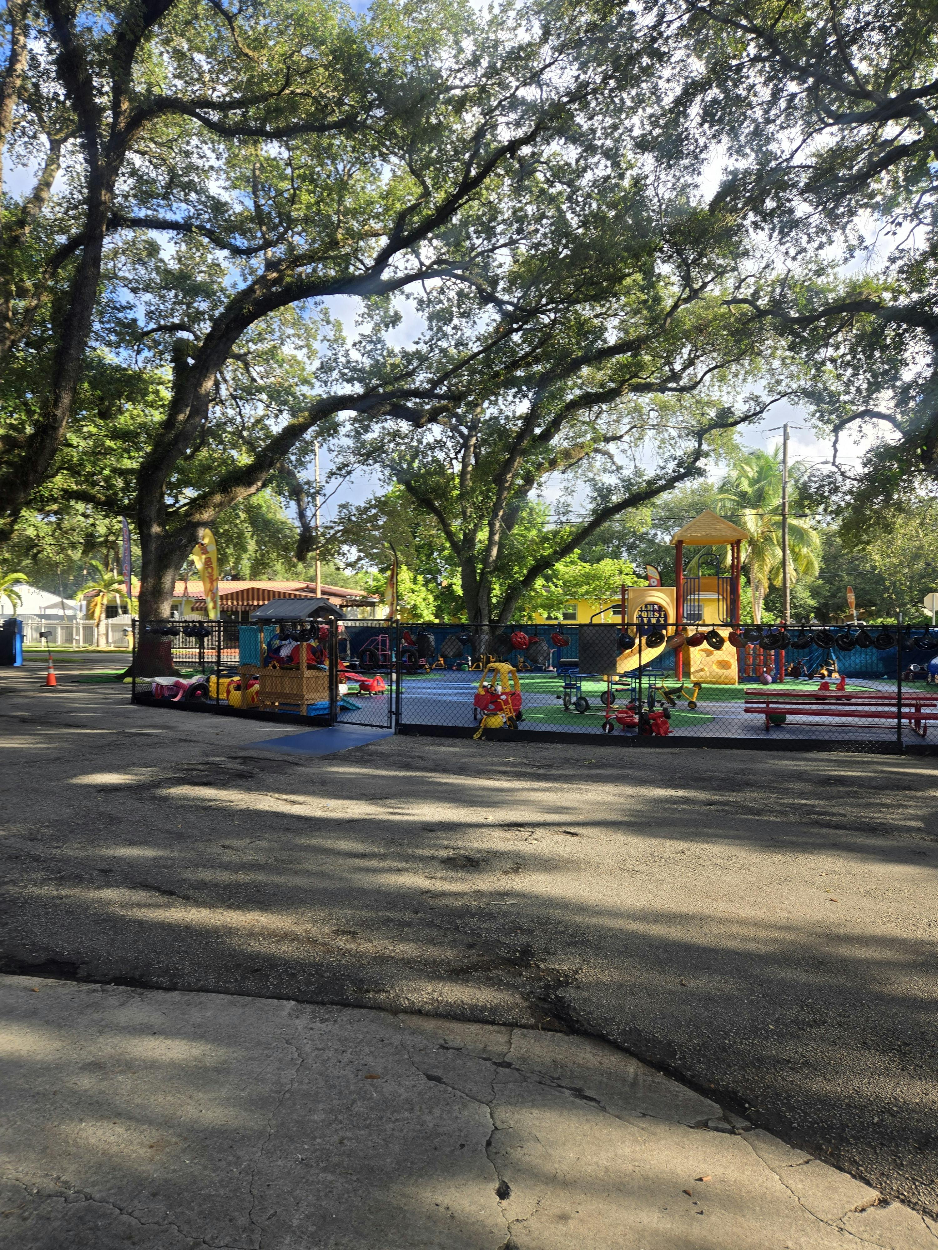 Outdoor playground with colorful equipment under large trees