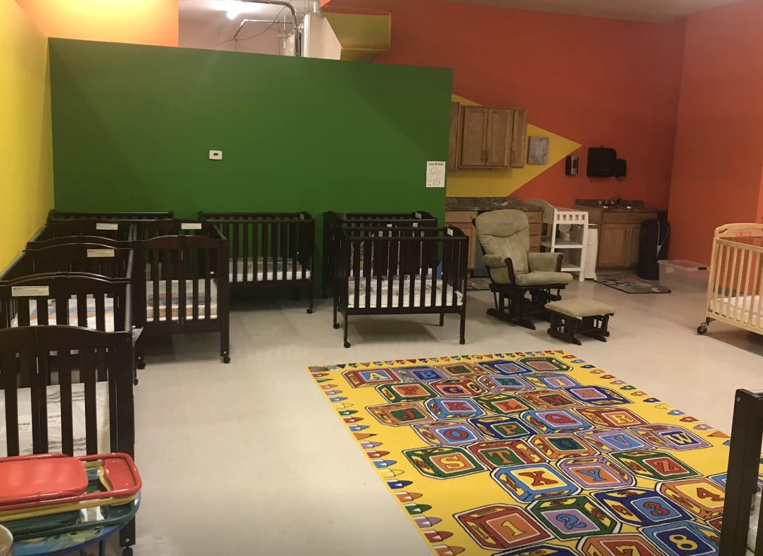 Room with multiple cribs and a colorful alphabet rug