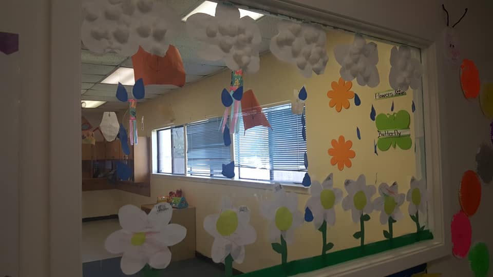 Window decorated with paper clouds, raindrops, flowers, and suns