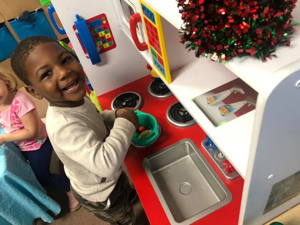 Child playing with a toy kitchen set