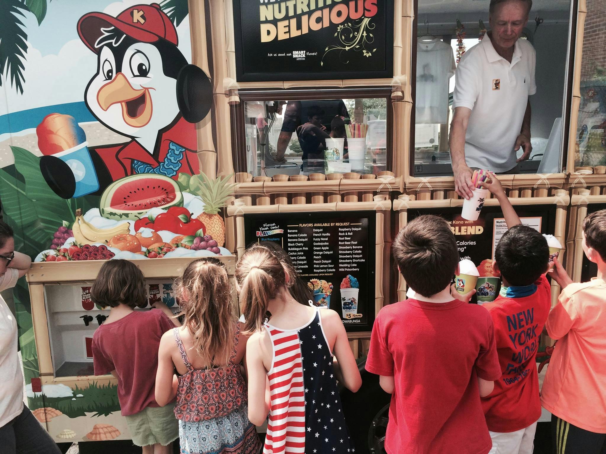 Children at a food stand receiving drinks from a person