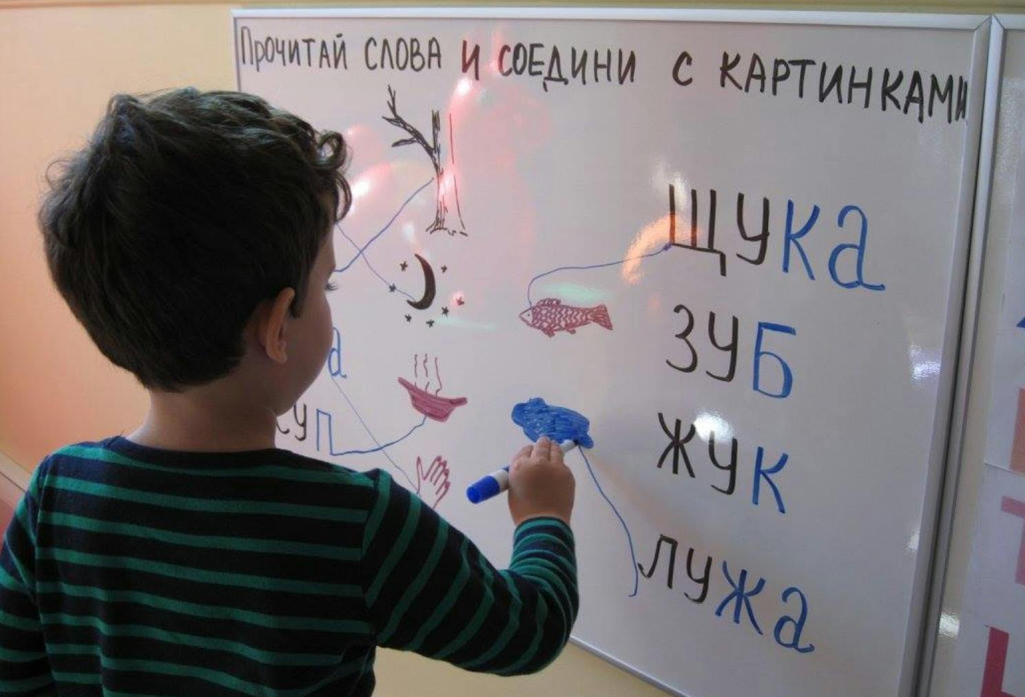 Child drawing on a whiteboard with words and pictures