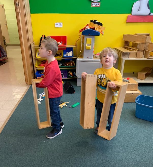 Two children holding wooden blocks in a classroom