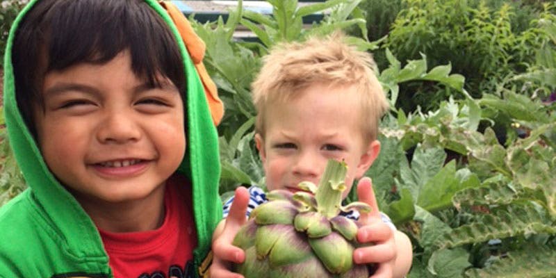 Two children holding an artichoke