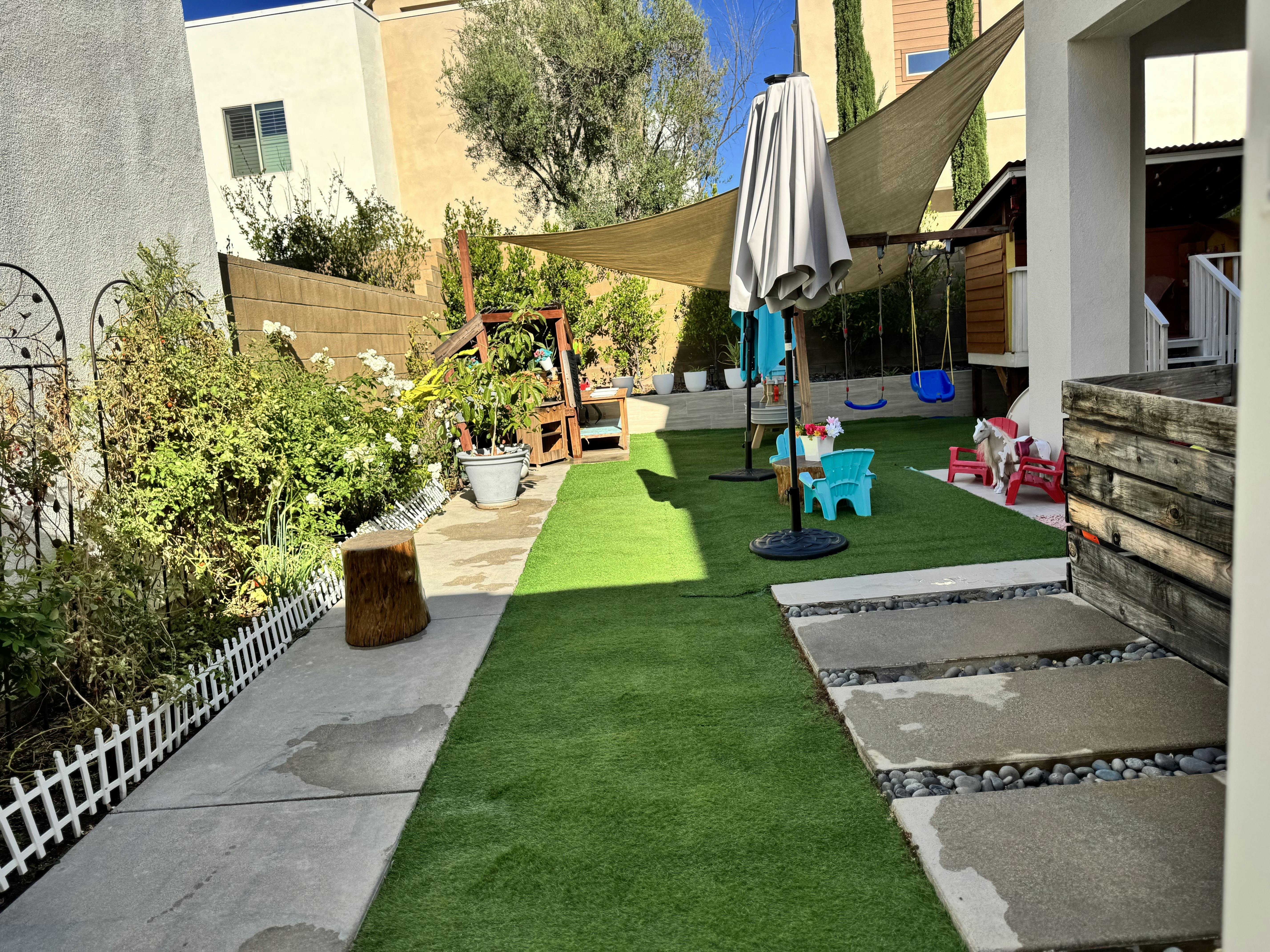 Backyard with artificial grass, patio furniture, and a shade sail