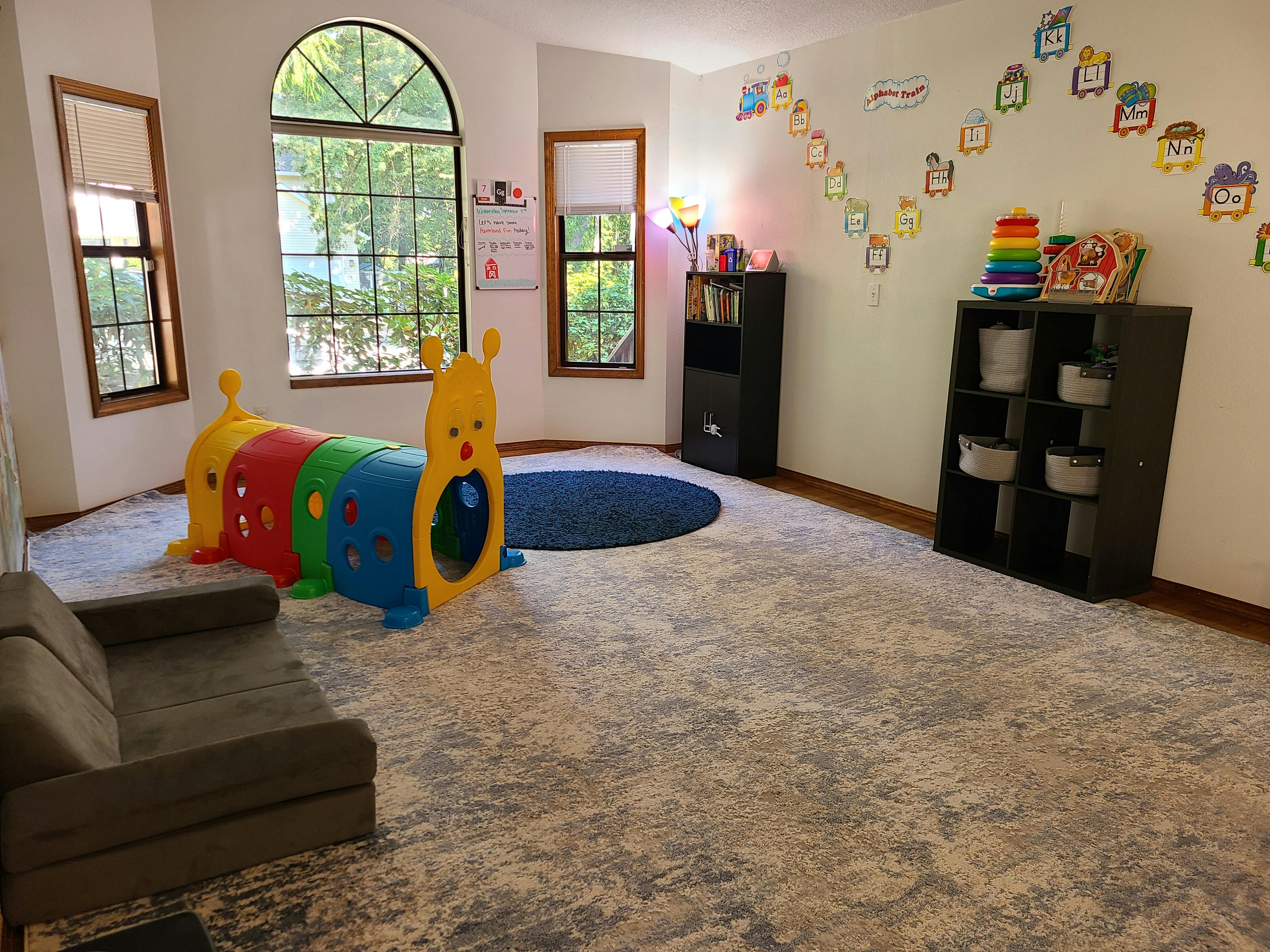 Playroom with a colorful caterpillar tunnel, sofa, and shelves with shelves of windows