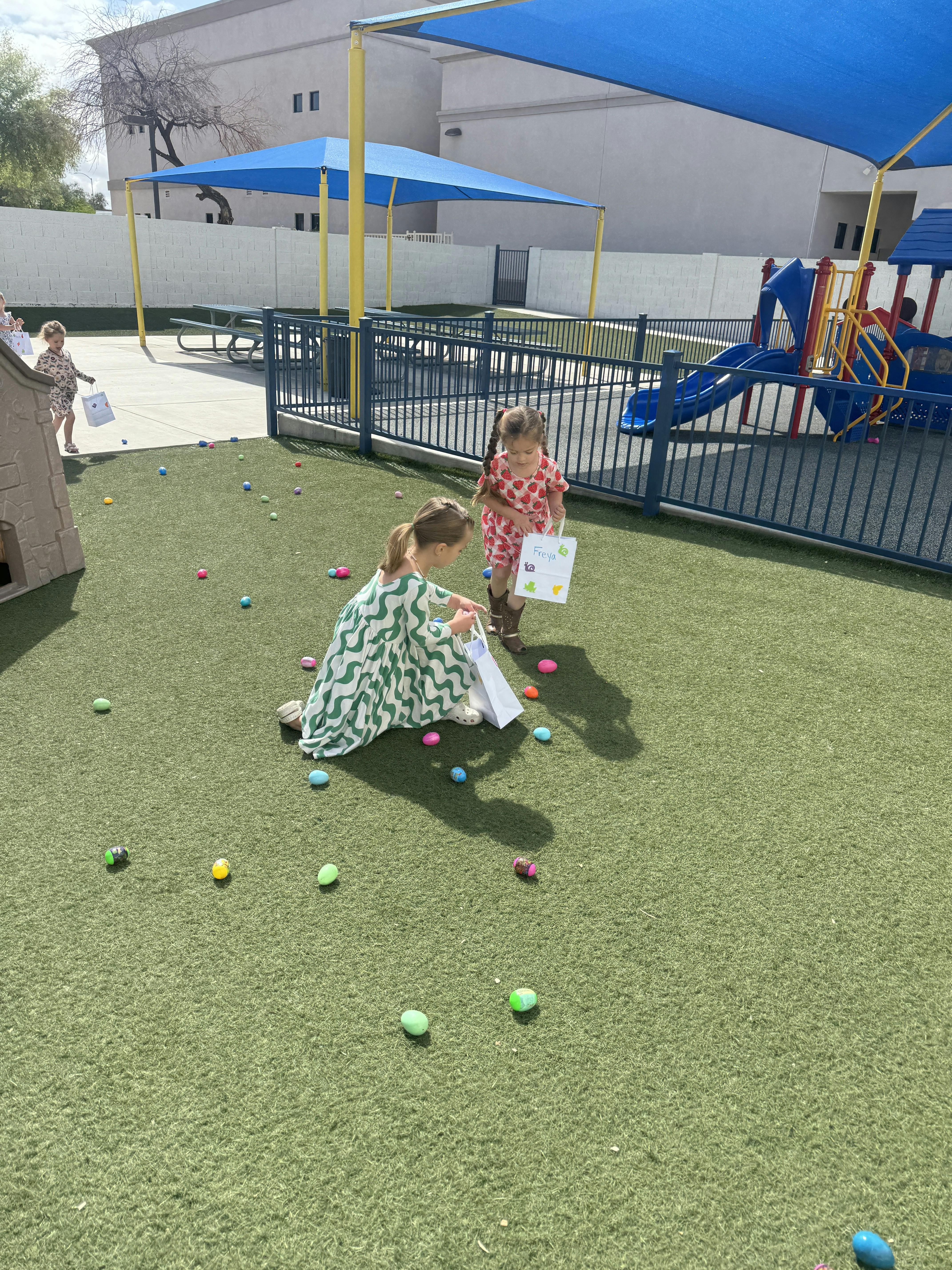 Children collecting colorful eggs on a grassy area