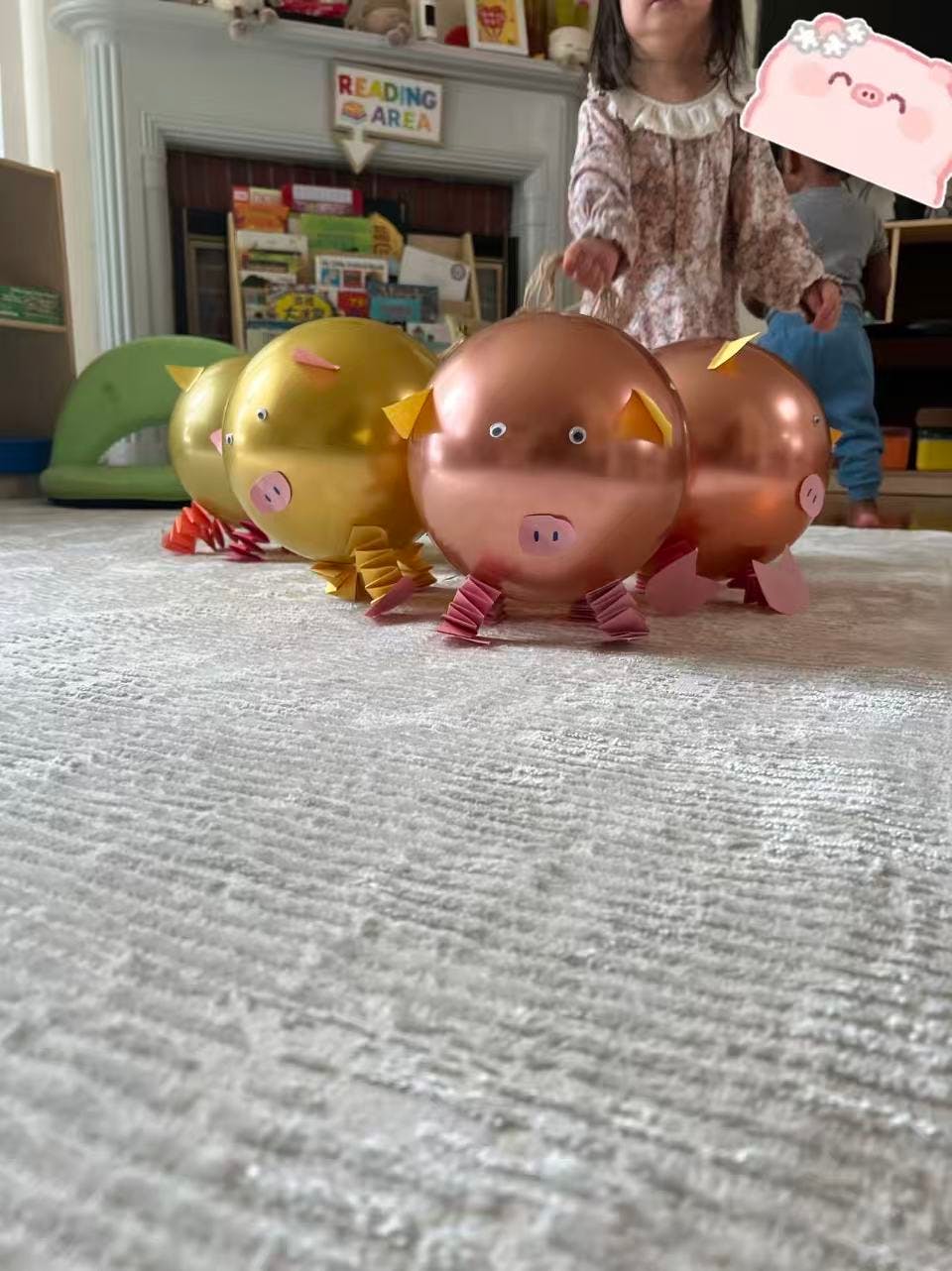 Child standing behind pig-shaped balloons on a rug