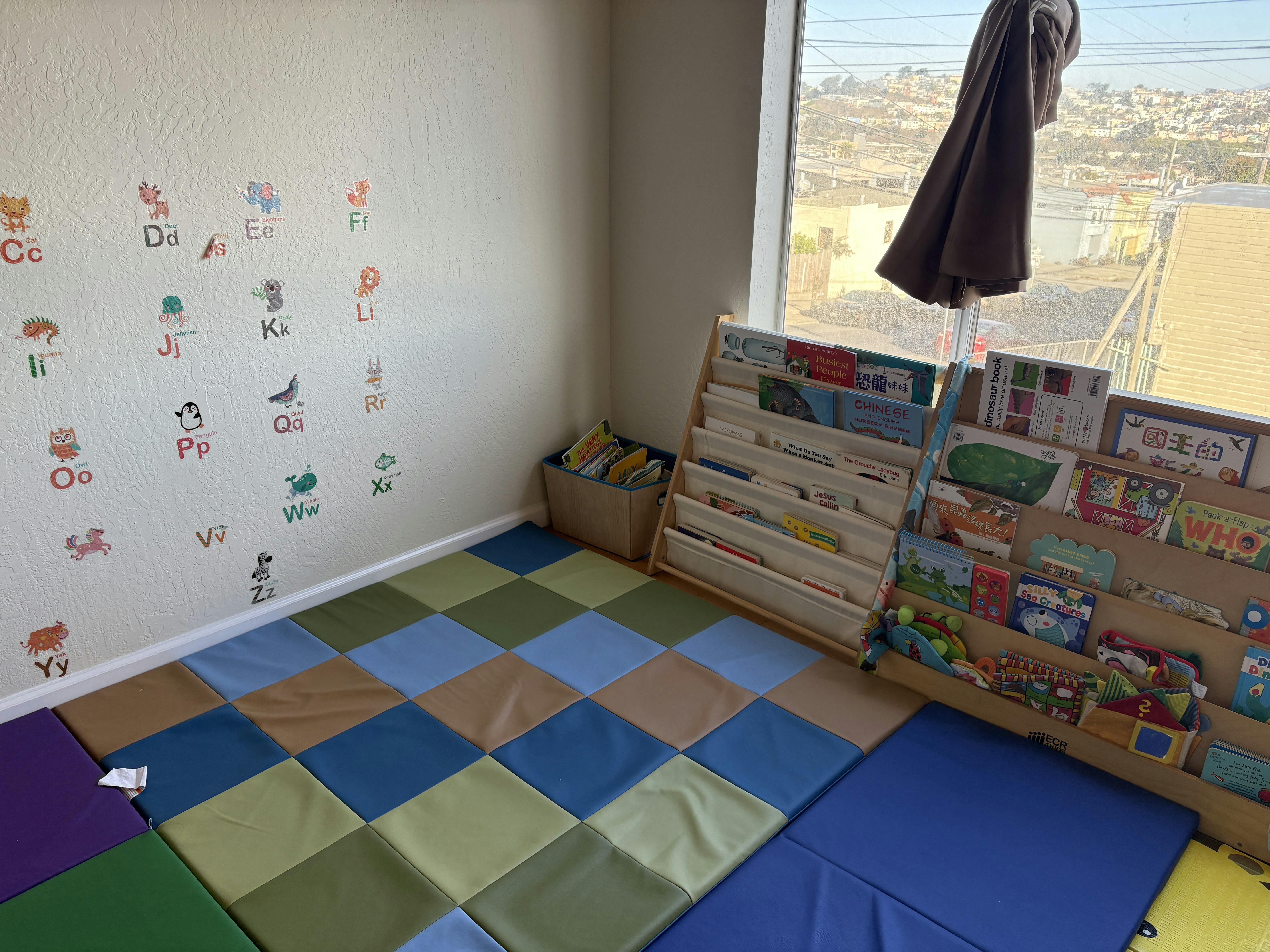 A children's reading nook with wall alphabet decals, soft floor mats, and books