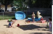 Children playing in a sandbox with a small pool and toys