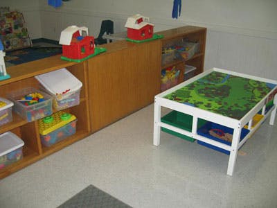 Playroom with toy storage shelves and a white play table