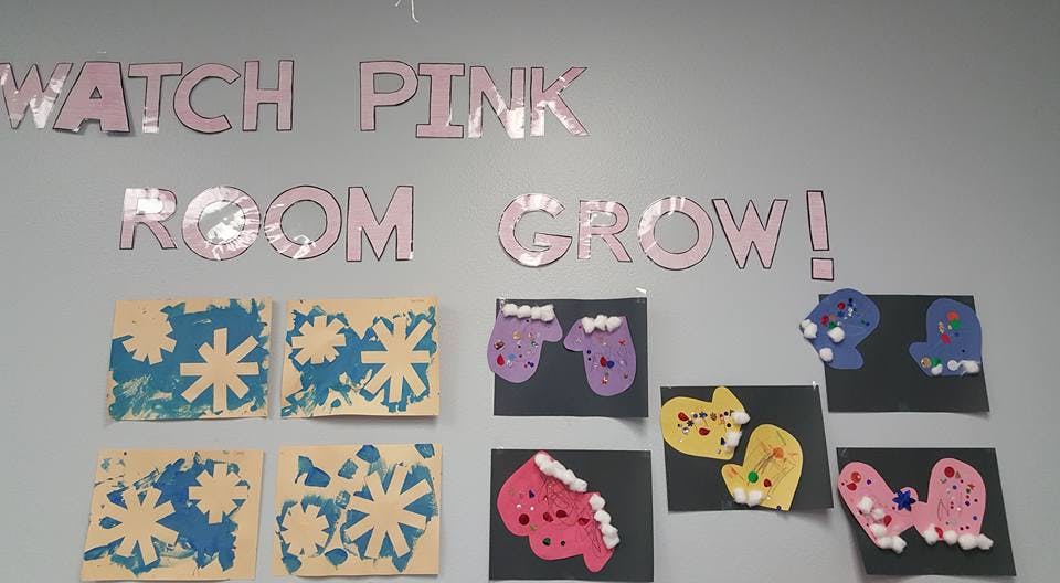 Children's artwork of snowflakes and mittens on a wall with text "WATCH PINK ROOM GROW!"