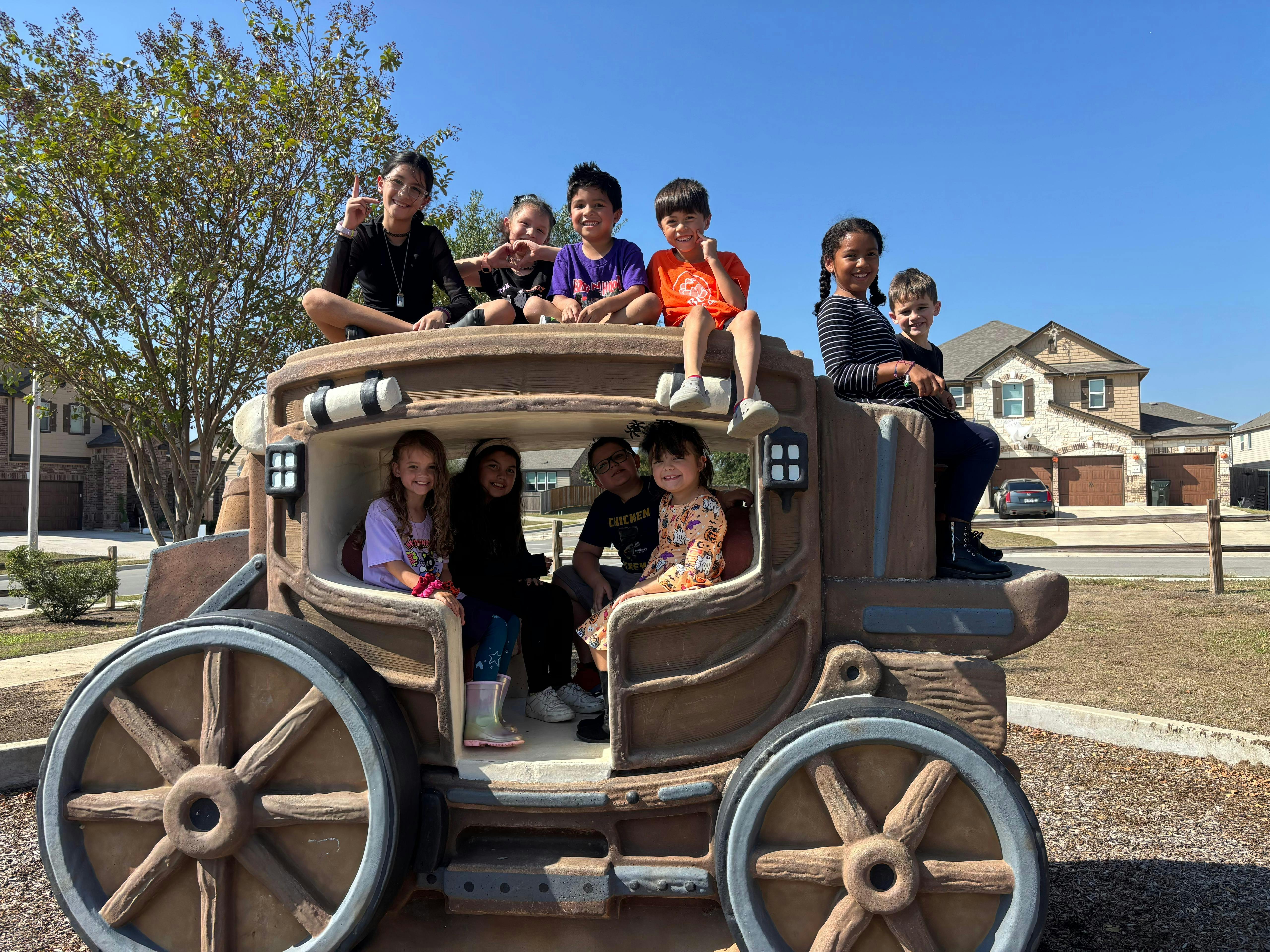 Group of children playing on a wagon-shaped playground structure