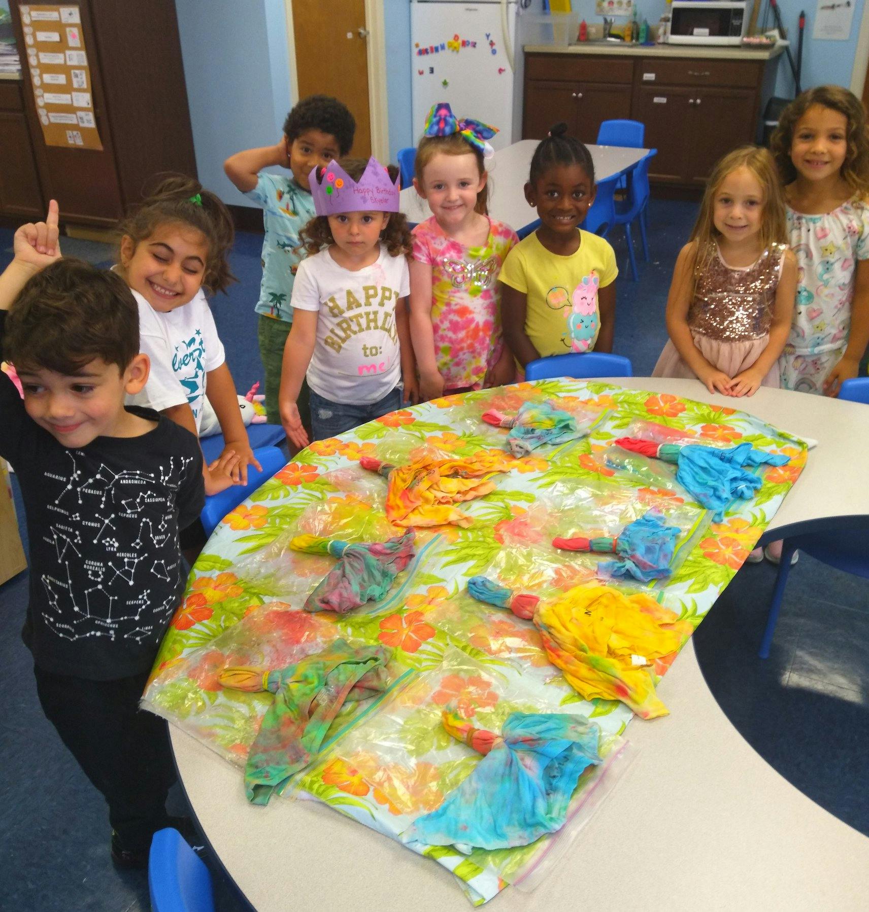 Children standing around a table with colorful items on it