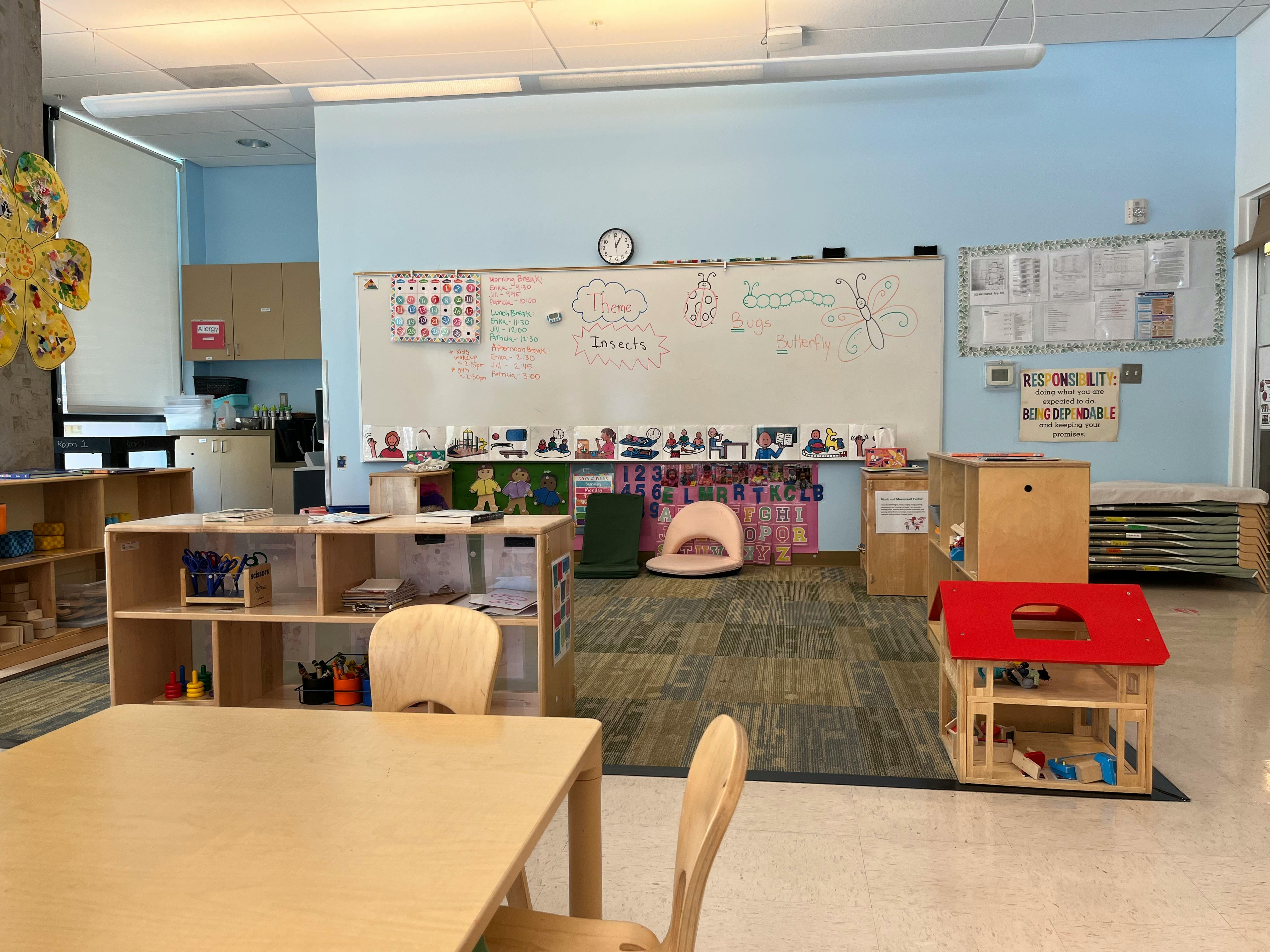 Classroom with tables, chairs, shelves, and a whiteboard