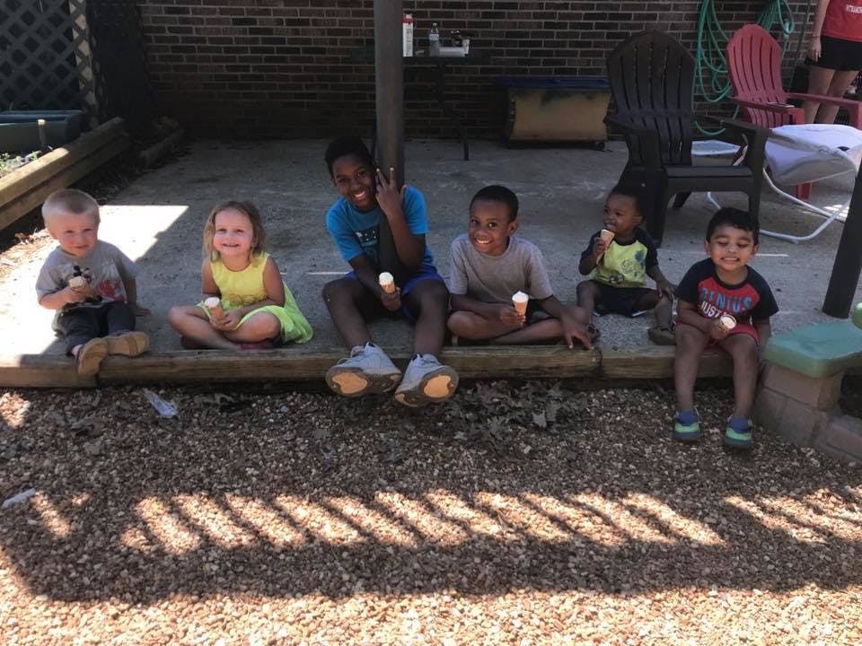 Five children sitting outdoors holding ice cream cones