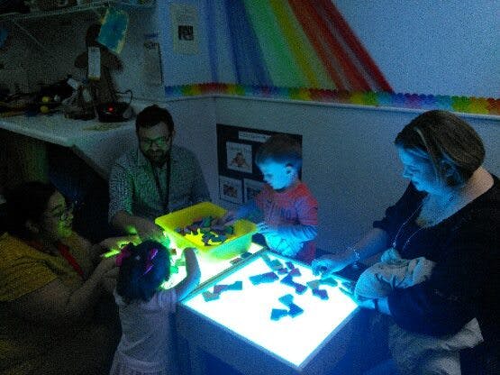 People and children playing with blocks on a light table