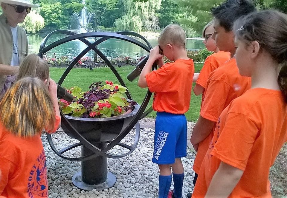 Children looking at a display of plants in a metal sphere