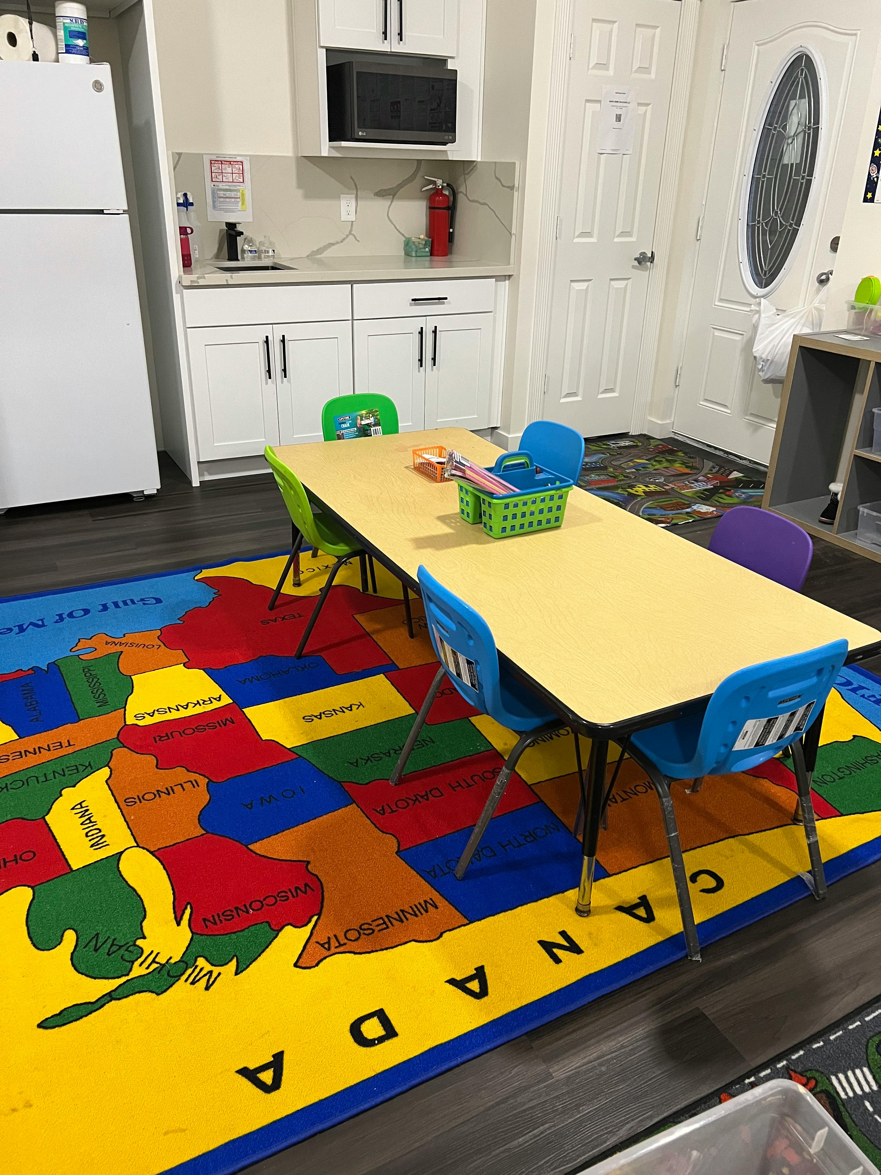 Classroom with a long table, chairs, and a map rug