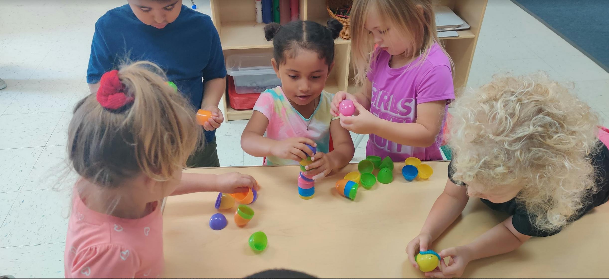 Children playing with colorful plastic eggs at a table