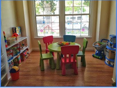 Playroom with small table and chairs, toy shelf, and window