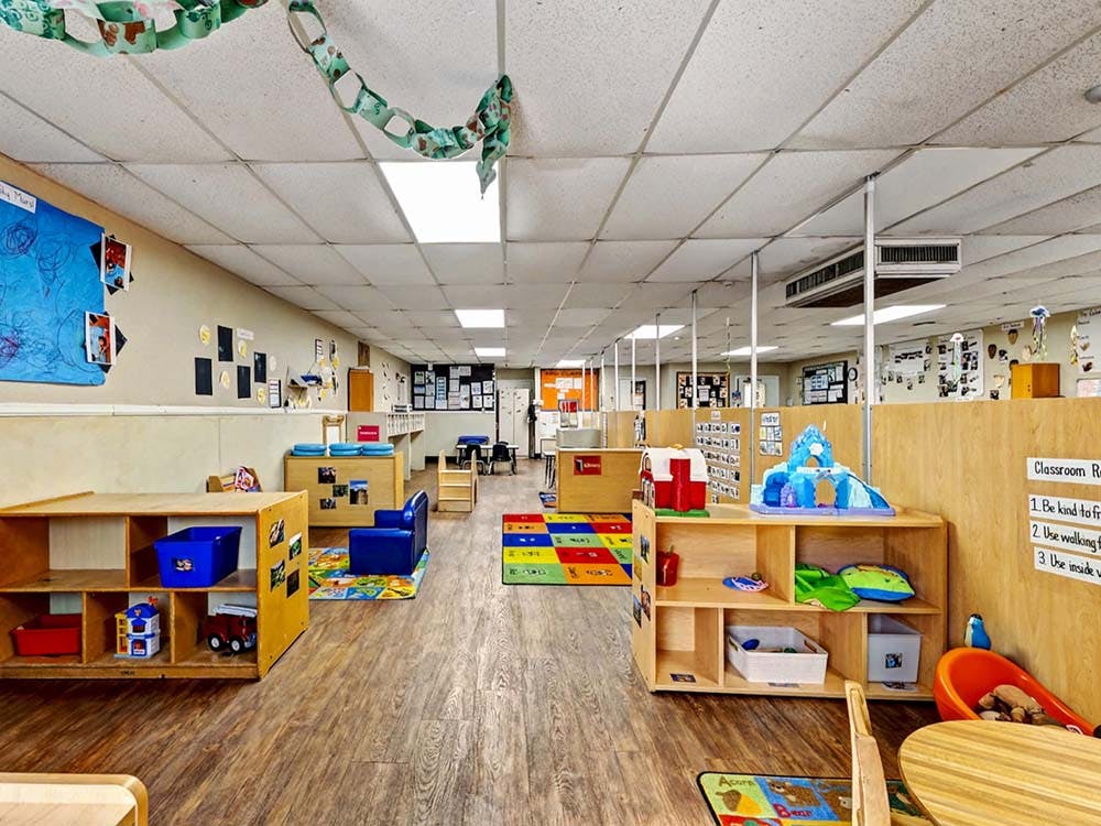 Empty colorful children's classroom with small wooden shelves and play areas