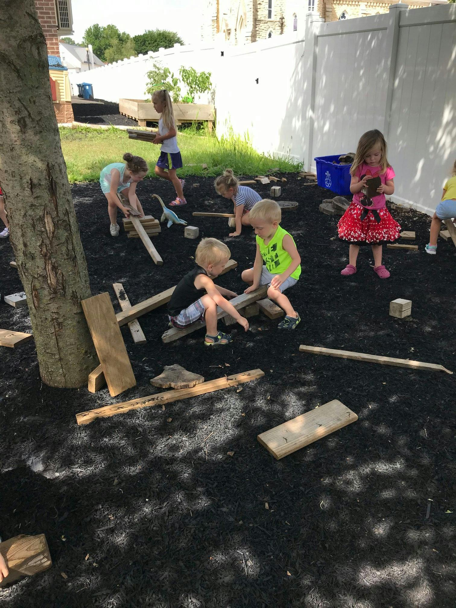 Children playing with wooden planks outdoors