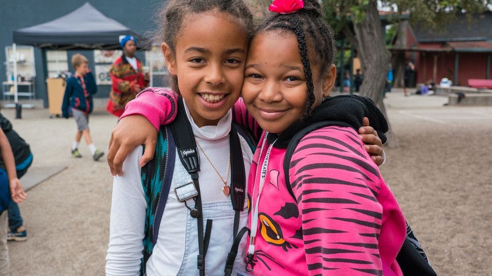 Two children with backpacks smiling