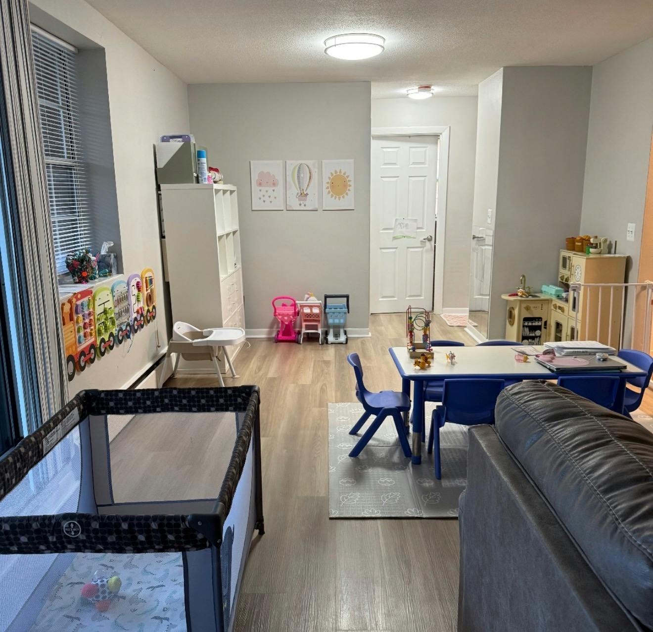 Childcare play area with crib, small table and chairs, and toy kitchen