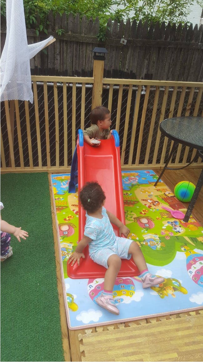 Two children playing on a red slide on a colorful mat