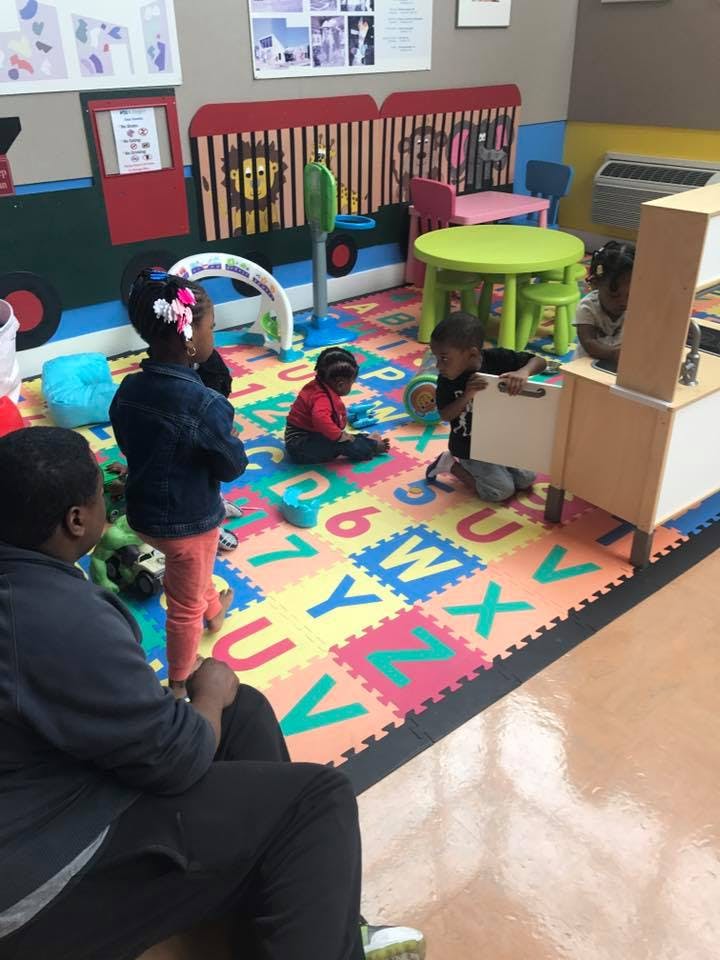 Children playing on an alphabet mat in a classroom
