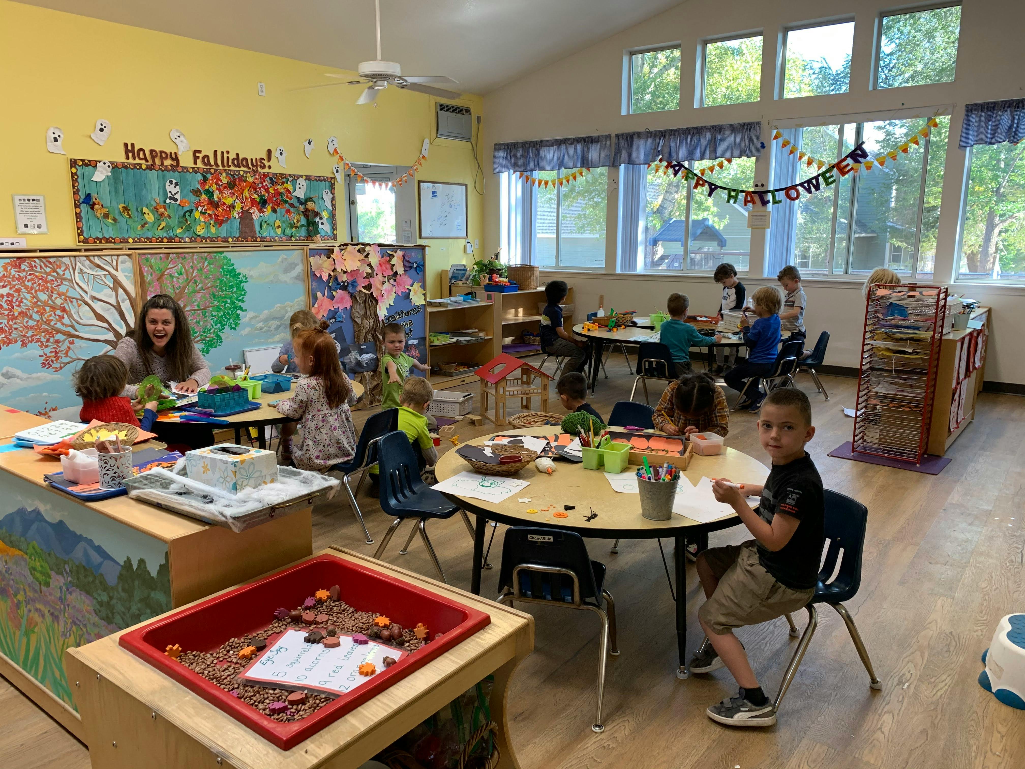 People and children in a classroom with tables and chairs
