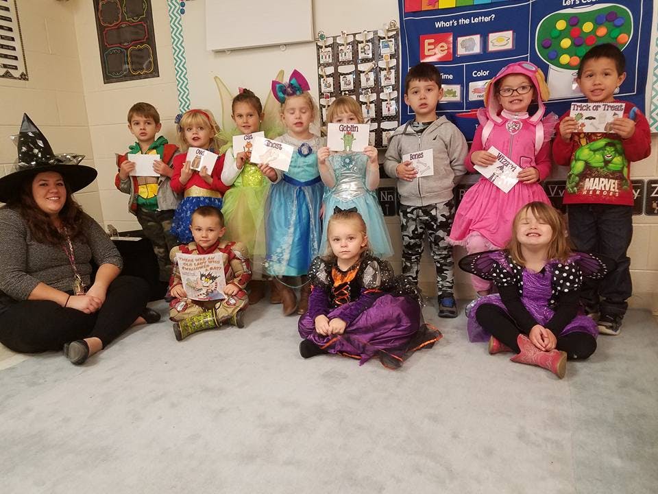 Person in witch hat with children in costumes holding papers