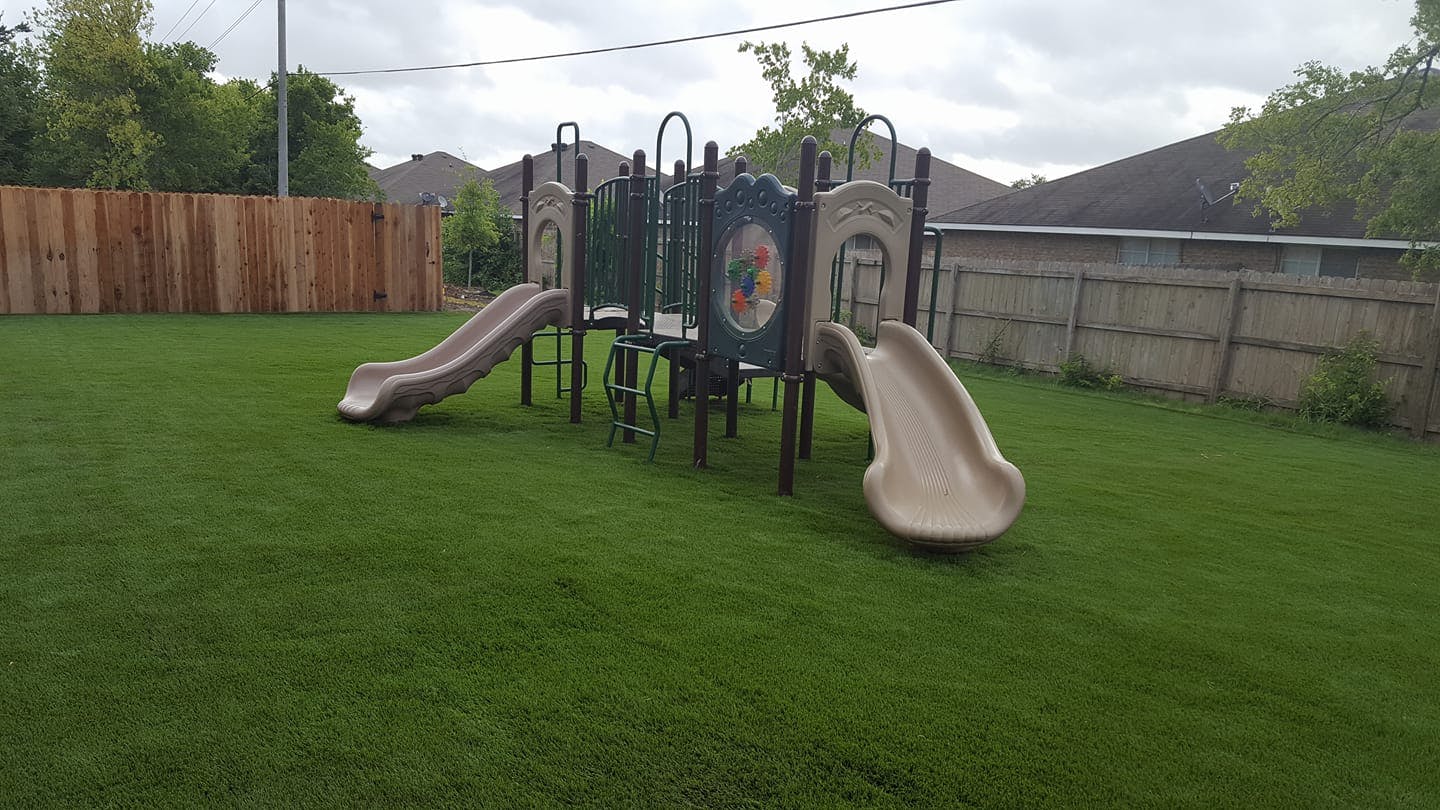 Playground structure with two slides on a grassy lawn