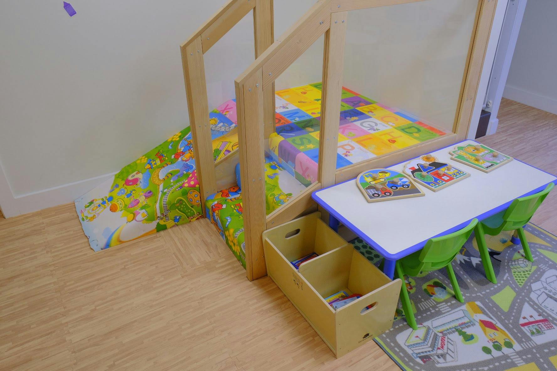 Play area with a small slide, table, chairs, and storage bins